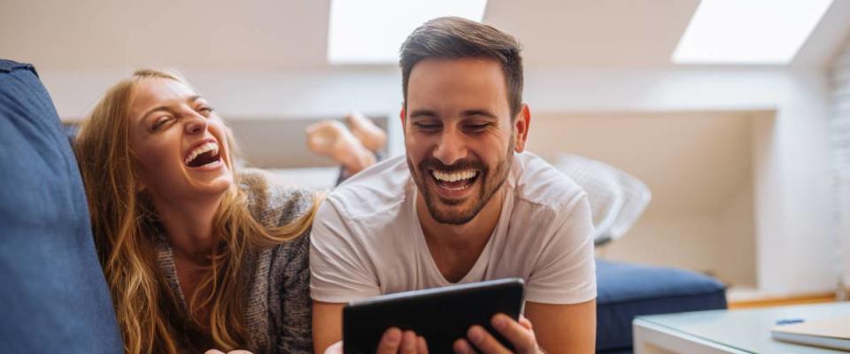 young couple laughing at home on bed