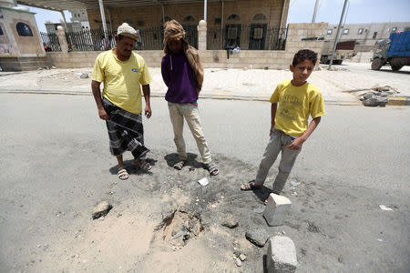 People stand by a crater caused by a Katyusha missile fired by the Houthis in the city of Marib, Yemen May 22, 2018. REUTERS/Ali Owidha