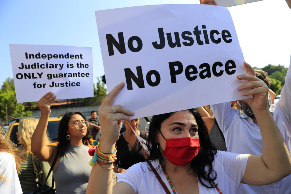 FILE - In this July 12, 2021 file photo, supporters of families who had relatives killed in last year's massive blast at Beirut's seaport, hold placards during a protest in support of legal action near the blast scene, in Beirut, Lebanon. For eight months Tarek Bitar, a relatively obscure judge has quietly investigated one of the world's worst non-nuclear explosions with only two assistants helping him -- and a lot of powerful detractors blocking him. For many Lebanese Bitar is their only hope for truth and accountability in a country that craves both. But for the country's entrenched political class, the 47-year-old Bitar has become a nightmare that needs to be dealt with.(AP Photo/Hussein Malla, File)