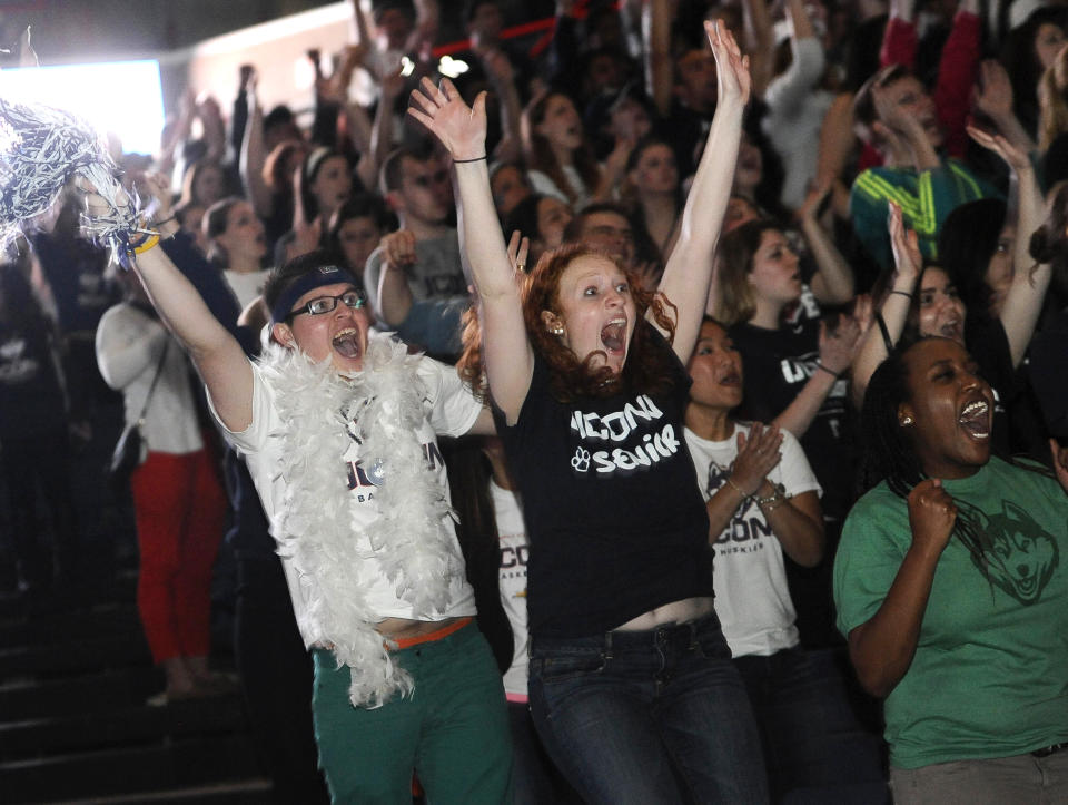 Husein Becirovic of New Britain, Conn., left, Laura Purcell of Stoughton, Mass., center, and Yvonne Ambenge of Mansfield, Conn., right, cheer as they watch the broadcast of the UConn and Notre Dame women's basketball game for the NCAA title, Tuesday, April 8, 2014, in Storrs, Conn. (AP Photo/Jessica Hill)