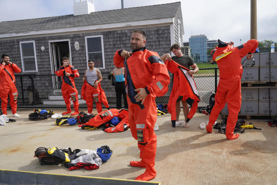 Lucas Drake, center, and other classmates get on waterproof suits before entering the water during a Global Wind Organisation certification class at the Massachusetts Maritime Academy in Bourne, Mass., Thursday, Aug. 4, 2022. At the 131-year-old maritime academy along Buzzards Bay, people who will build the nation's first commercial-scale offshore wind farm are learning the skills to stay safe while working around turbines at sea. (AP Photo/Seth Wenig)