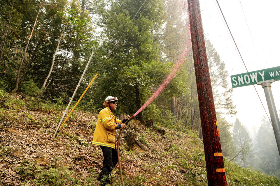 Pacific Gas & Electric firefighter Dave Ronco sprays retardant on a utility pole to protect infrastructure as the Mosquito Fire burns near Volcanoville in El Dorado County, Calif., on Friday, Sept. 9, 2022. (AP Photo/Noah Berger)