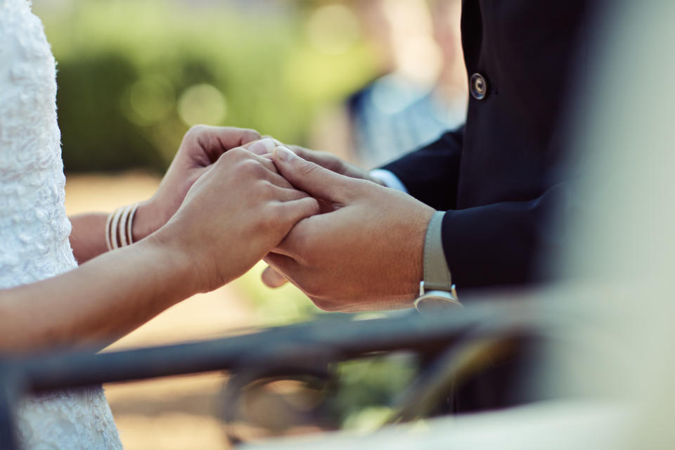 A couple hold hands as they exchange vows on their wedding day