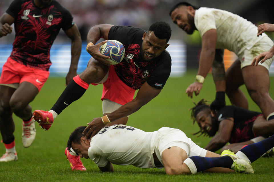 Fiji's Vilimoni Botitu jumps over England's Alex Mitchell during the Rugby World Cup quarterfinal match between England and Fiji at the Stade de Marseille in Marseille, France, Sunday, Oct. 15, 2023. (AP Photo/Daniel Cole)