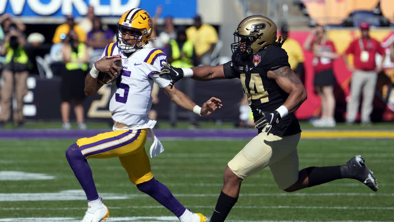 LSU quarterback Jayden Daniels (5) scrambles to get past Purdue defensive end Kydran Jenkins, right, during the first half of the Citrus Bowl NCAA football game Monday, Jan. 2, 2023, in Orlando, Fla. American Athletic Conference commissioner Mike Aresco believes the Power 5/Group of 5 labels “should be discarded and confined to the dustbin of collegiate history.”