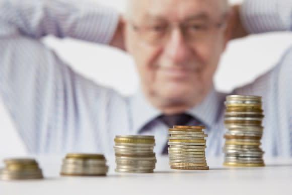 Satisfied person looking at a growing stack of coins.