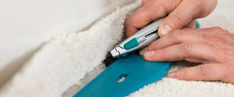 Close-up Of A Craftsman Cutting Carpet With Cutter