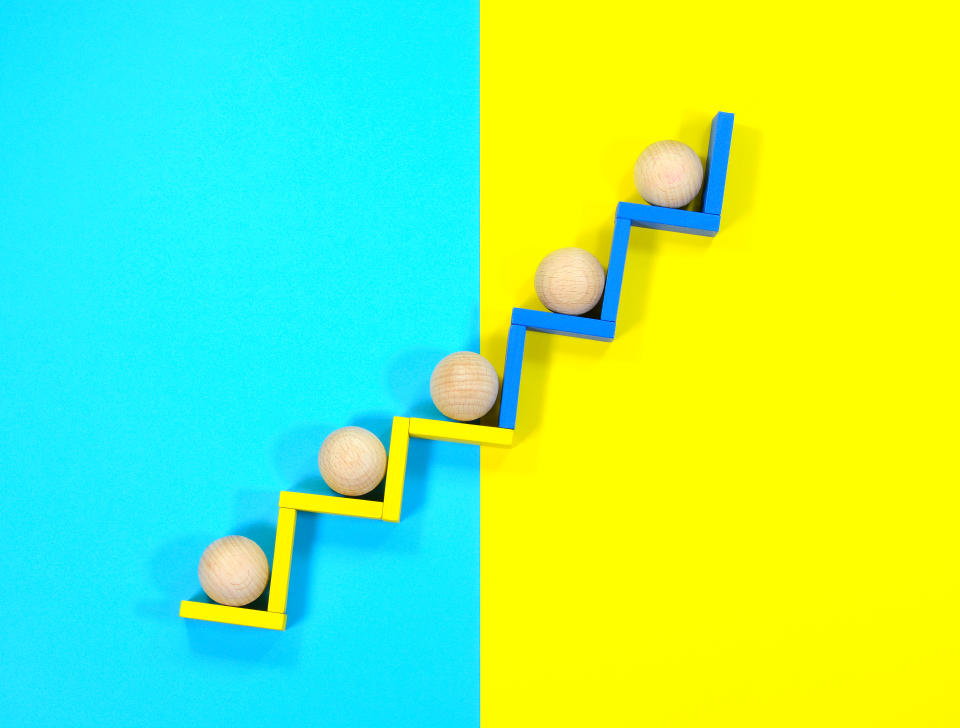 Image of five round wooden balls moving up steps to represent growth.