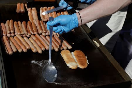 A man cooks hot dogs from the vendor Walter's during the opening of an exhibit at Ellis Island highlighting the immigrant history behind the "Hot Dog" in New York City, U.S., June 28, 2017. REUTERS/Lucas Jackson