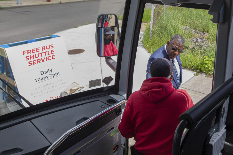 Tommy Seay Sr., a driver with Niagara Scenic Tours, helps a shopper off the bus at a pickup spot, Tuesday, May 17, 2022, in Buffalo, N.Y. In an effort to help shoppers who live near the Tops Friendly Markets location closed due to the shooting, Tops is offering a shuttle to transport people to another location miles away to shop. (AP Photo/Joshua Bessex)