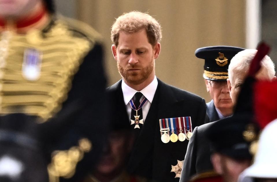 Prince Harry, Duke of Sussex walks behind the coffin of Queen Elizabeth II, adorned with a Royal Standard and the Imperial State Crown and pulled by a Gun Carriage