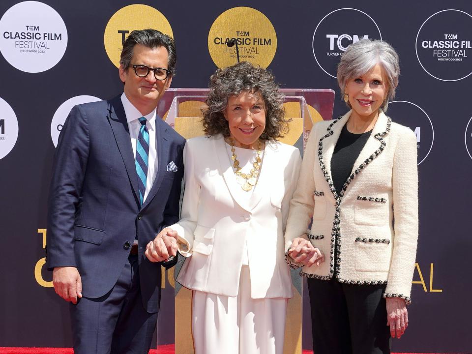 Ben, Lily, and Jane smiling and holding hands in front of a backdrop.