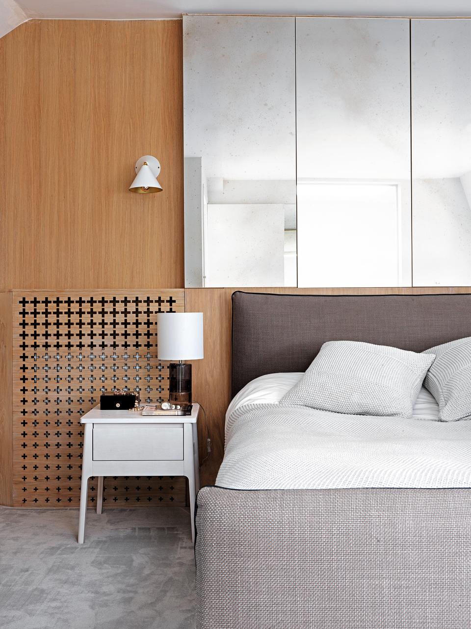 A neutral, minimalist bedroom with a wood panelled wall