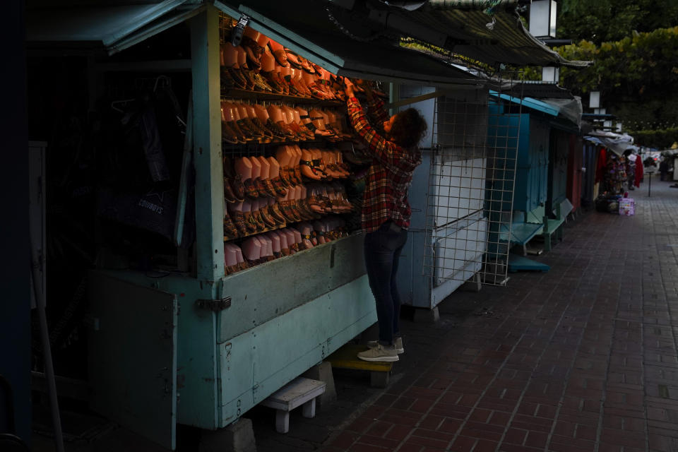 A merchant closes her shop for the day on Olvera Street in downtown Los Angeles, Tuesday, Dec. 15, 2020. Olvera Street, known as the birthplace of Los Angeles, has been particularly hard hit by the coronavirus pandemic, with shops and restaurants closed and others barely hanging on. Only a handful of businesses remain open on weekdays as tourism has cratered and downtown offices are closed and festive events held throughout the year have been canceled. (AP Photo/Jae C. Hong)