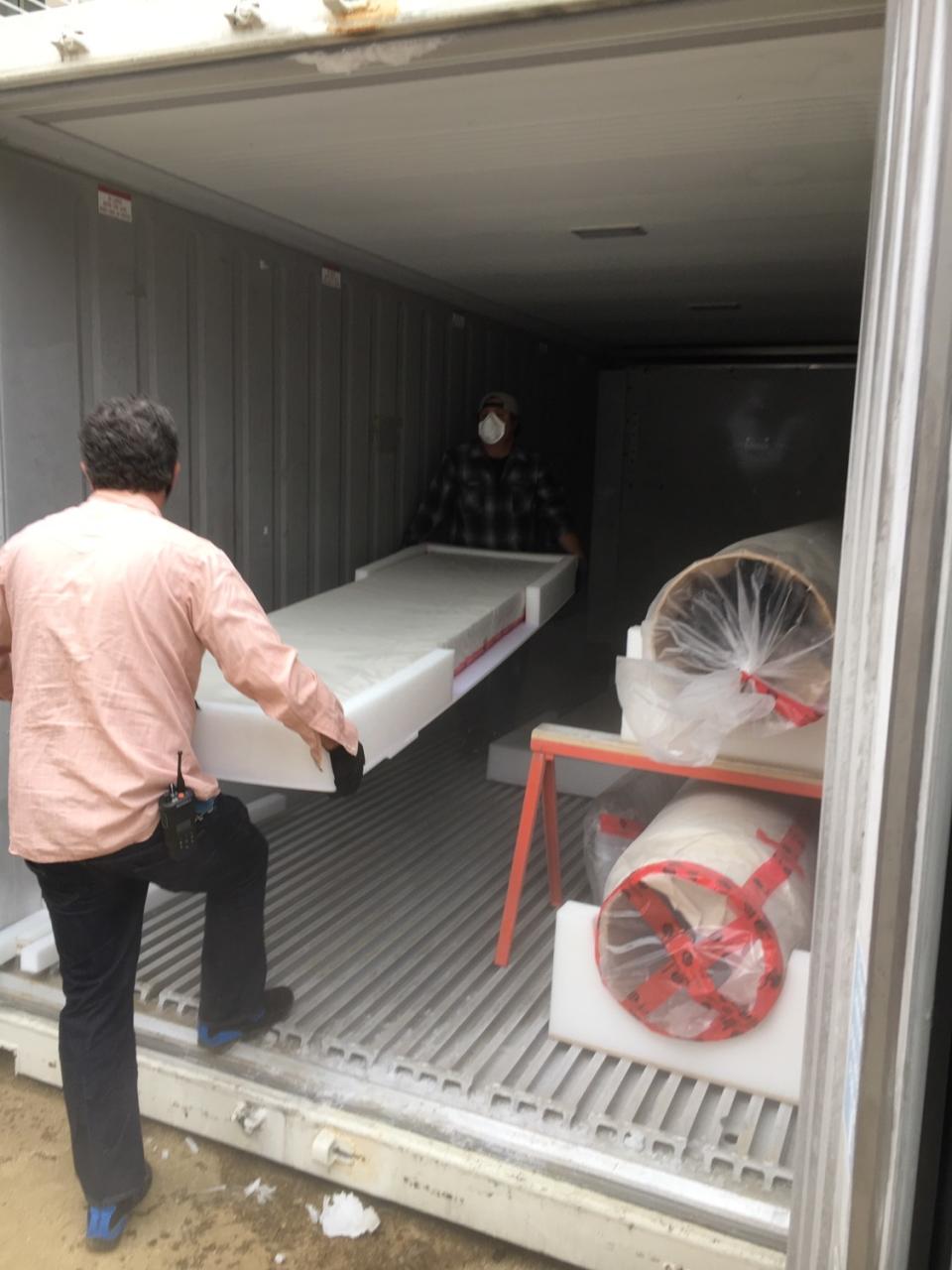 Team members carry a cradled artwork into a mobile freezer.