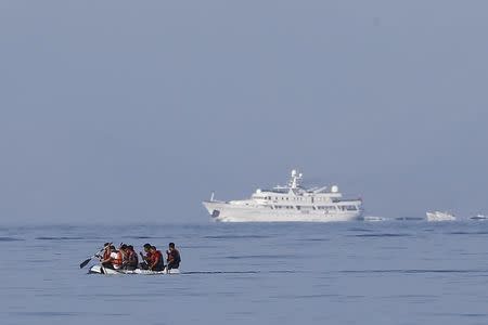 Migrants in a dinghy paddle past a luxury yacht which cruises on Mediterrean Sea as they attempt a crossing to the Greek island of Kos, off the shores of Bodrum, Turkey, September 19, 2015. REUTERS/Umit Bektas