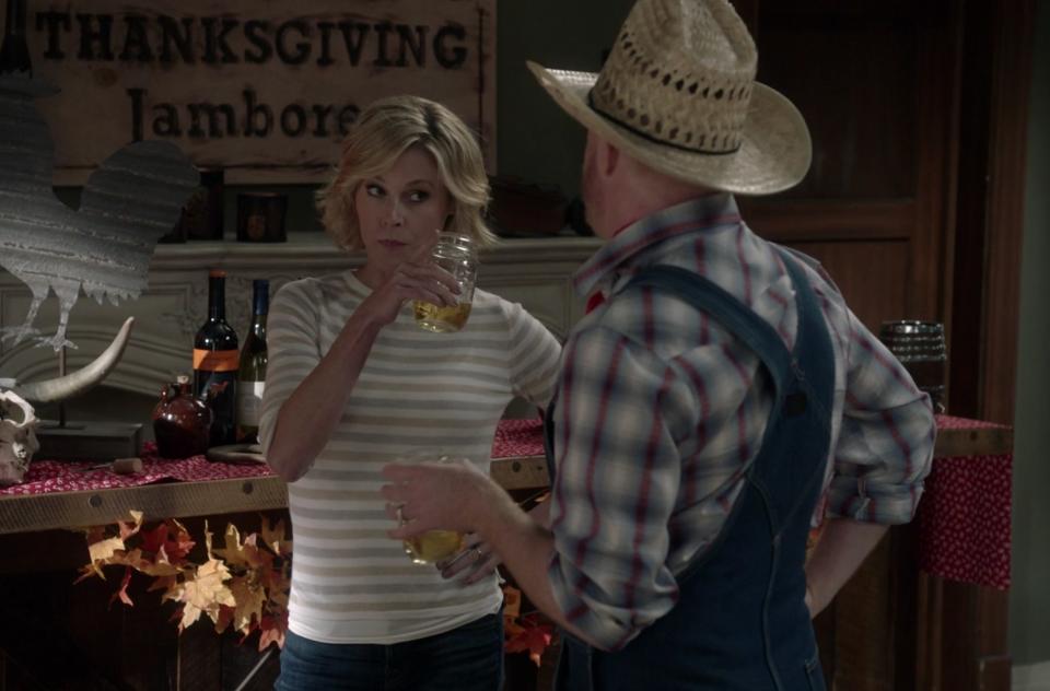 Claire points her mason jar of wine at Mitchell, who's dressed like a farm hand