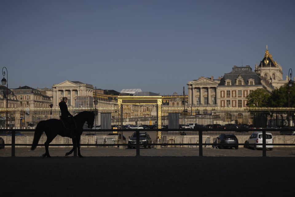 Laure Guillaume, 44, horsewoman and coordinator at the AcadÈmie du Spectacle Equestre trains with her horse in the main courtyard of the royal stables, in Versailles, Thursday, April 25, 2024. More than 340 years after the royal stables were built under the reign of France's Sun King, riders and horses continue to train and perform in front of the Versailles Palace. The site will soon keep on with the tradition by hosting the equestrian sports during the Paris Olympics. Commissioned by King Louis XIV, the stables have been built from 1679 to 1682 opposite to the palace's main entrance. (AP Photo/Aurelien Morissard)