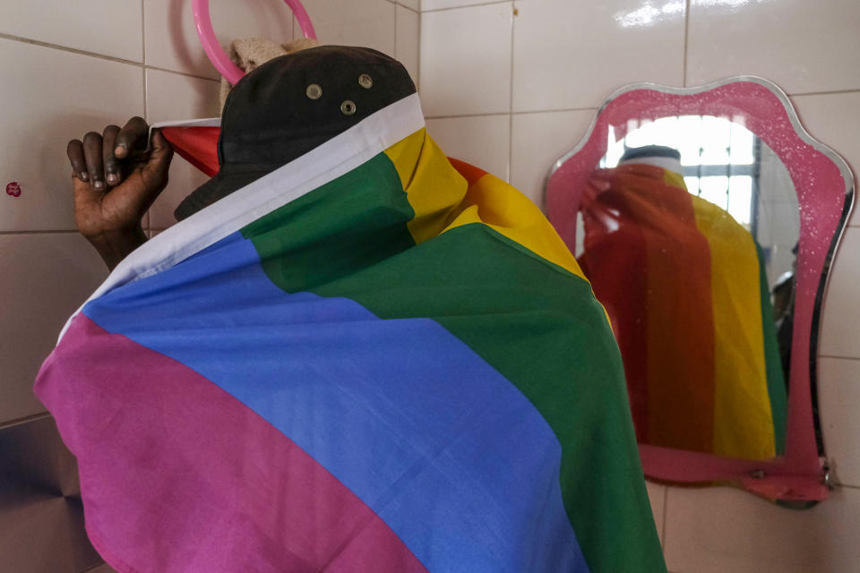 A gay Ugandan man covers himself with a pride flag as he poses for a photograph in Uganda Saturday, March 25, 2023. A prominent leader of Uganda's LGBTQ community on Thursday described anguished calls by others like him who are concerned for their safety after the passing of a harsh new anti-gay bill. (AP Photo)