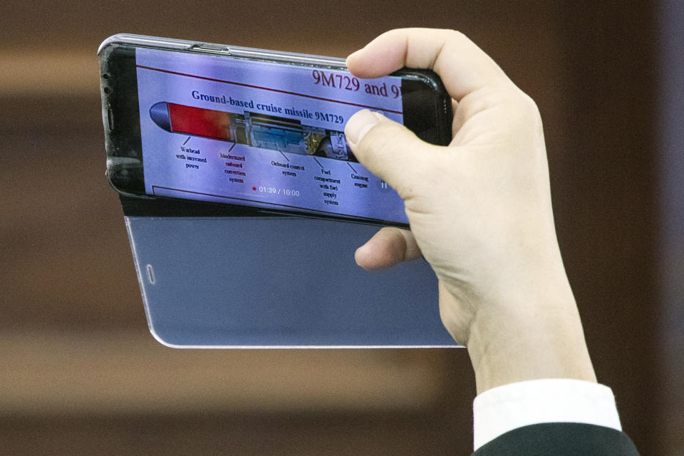 A foreign military attache takes picture of an image showing the 9M729 land-based cruise missile during a briefing by the Russian Defense Ministry in Kubinka outside Moscow, Russia, Wednesday, Jan. 23, 2019. The Russian military on Wednesday rolled out its new missile and spelled out its specifications, seeking to dispel the U.S. claim that the weapon violates a key nuclear arms pact. (AP Photo/Pavel Golovkin)