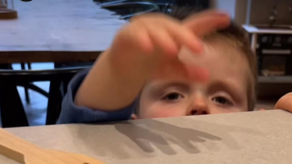 A young child reaching over a counter for a chocolate bar