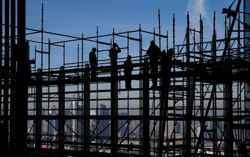 Construction workers are silhouetted while standing on scaffolding at the construction site of the new headquarters of the ECB during a guided media tour in Frankfurt