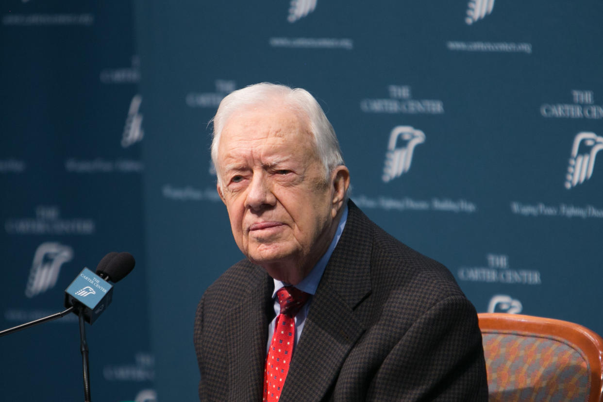 Former President Jimmy Carter sits before a microphone during a press conference.