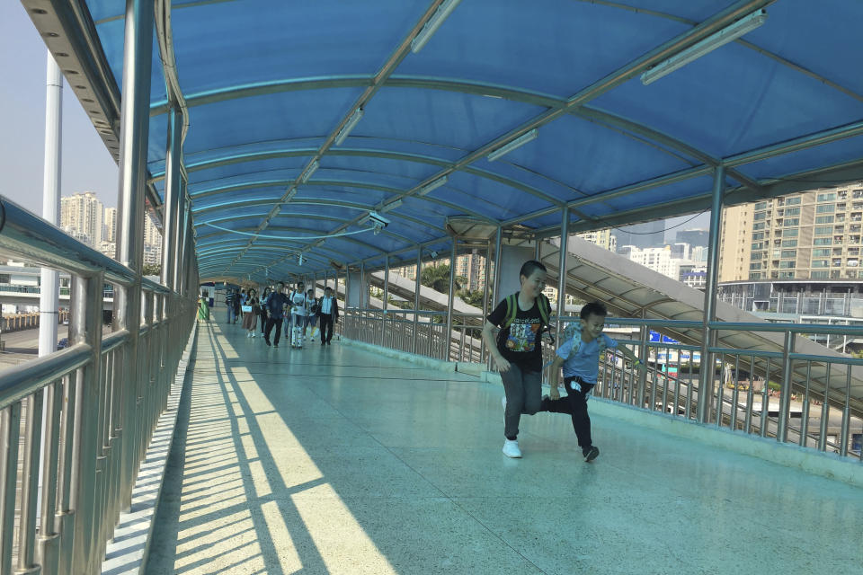 In this Friday, Nov. 15, 2019 photo, children run across a pedestrian bridge leading from Hong Kong at the Huanggang Port in Shenzhen in southern China's Guangdong Province. Since anti-government demonstrators in Hong Kong began barricading university campuses earlier this week, hundreds of mainland Chinese students have retreated to neighboring Shenzhen, where the ruling Communist Party's Youth League has promised them a "warm home." (AP Photo/Yanan Wang)