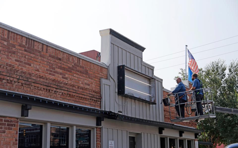 Workers work on a sign Wednesday at the former Mantel Wine Bar & Bistro in Oklahoma City.