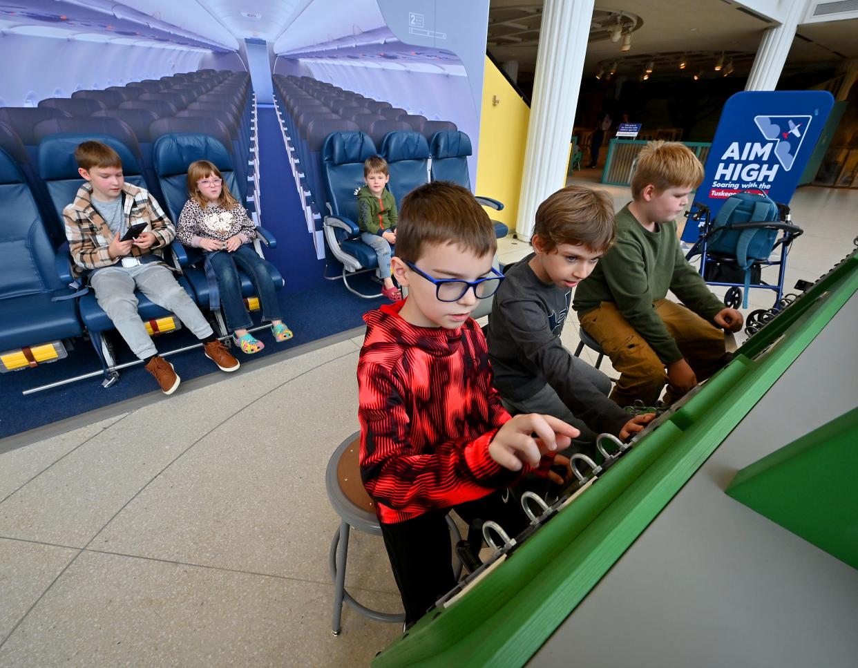 Luca Kamfonik, 8, of Brooklyn, Conn., Bryce Lambert, 8, of Webster, and Branson Merrick, 11, of Thompson, Conn., play with the cockpit flight trainer as part of the exhibit "Aim High: Soaring with the Tuskegee Airmen" at the EcoTarium.