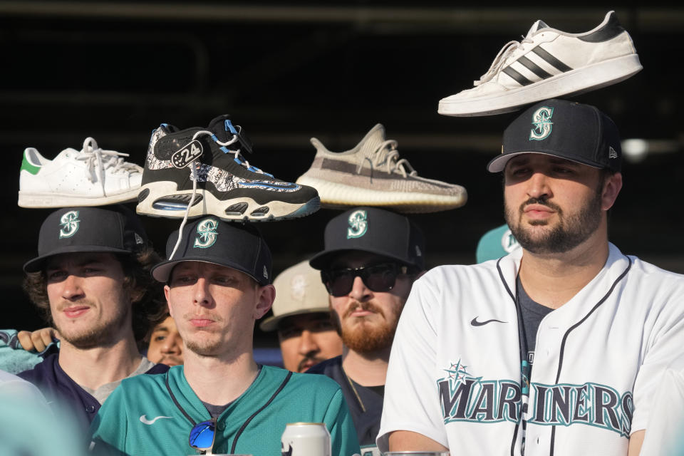 Seattle Mariners fans wear rally shoes on their heads during the eighth inning in Game 3 of an American League Division Series baseball game between the Seattle Mariners and the Houston Astros, Saturday, Oct. 15, 2022, in Seattle. (AP Photo/Stephen Brashear)