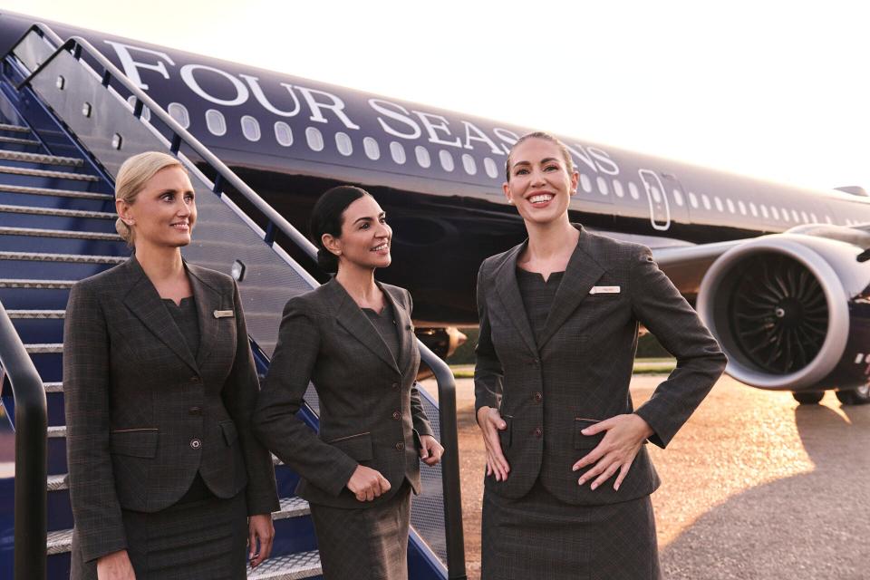 Three Four Seasons employees wearing black suits stand in front of the firm's Airbus A321LR