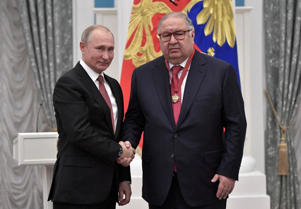 Alisher Usmanov (R) shakes hands with Russian president Vladimir Putin in 2018 (Reuters)