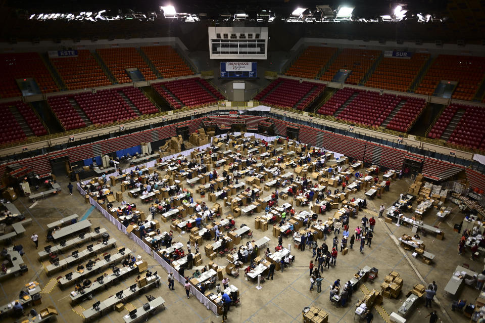 Officials count early votes at the Roberto Clemente Coliseum where social distancing is possible amid the COVID-19 pandemic, during general elections in San Juan, Puerto Rico, Tuesday, Nov. 3, 2020. In addition to electing a governor, Puerto Ricans are voting in a nonbinding referendum on statehood. (AP Photo/Carlos Giusti)