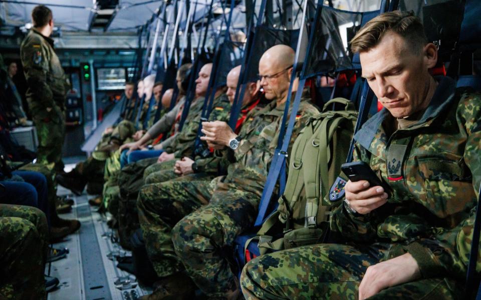一排穿着迷彩服的士兵坐在军用飞机上