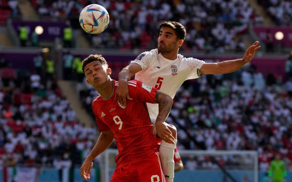 Wales' Brennan Johnson, left, and Iran's Milad Mohammadi fight for the ball during the World Cup group B soccer match between Wales and Iran - AP