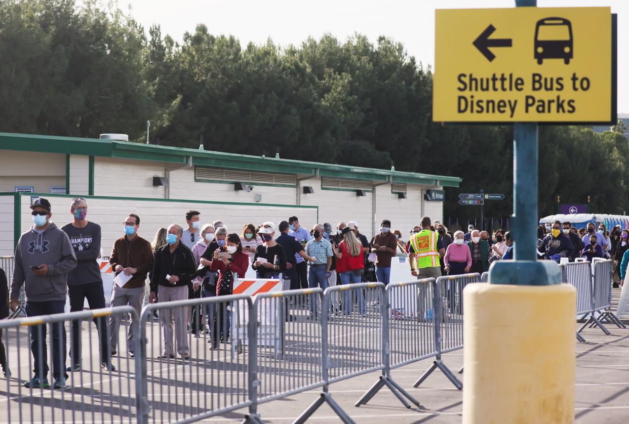 People wait in line to receive the COVID-19 vaccine at a mass vaccination site in a parking lot for Disneyland Resort on Jan. 13, 2021, in Anaheim, Calif.