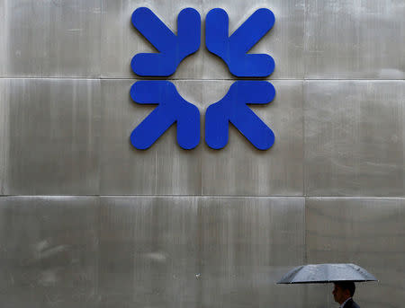 FILE PHOTO: A man shelters under an umbrella as he walks past a branch of the Royal Bank of Scotland in the City of London, Britain, September 17, 2013. REUTERS/Stefan Wermuth/File Photo