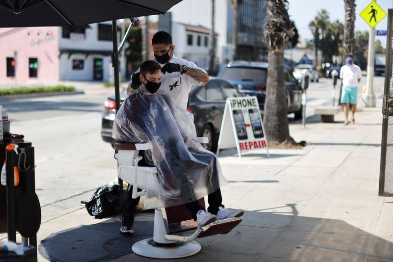 Keith Huerta, 30, cuts the hair of Nick Parr, 25, on the street outside Active Barbers, amid the global outbreak of the coronavirus disease (COVID-19), in Santa Monica