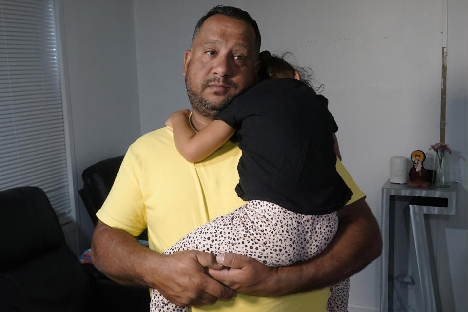 Victor Macedo holds his daughter Sonia at their home, Wednesday, Sept. 27, 2023, in Davie, Fla. The family crossed the border U.S. almost two years ago. Since then, they have been living in South Florida with the support of family and friends. They recently qualified for temporary protected status. (AP Photo/Marta Lavandier)