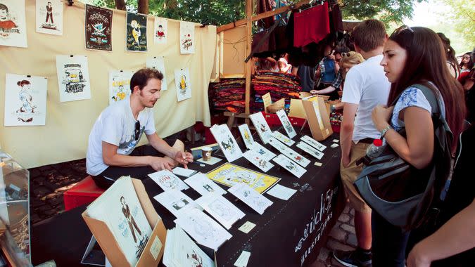 BERLIN, GERMANY - AUG 30, 2015: Young artist draws and sells graphic arts on street market in Mauerpark on August 30, 2015.