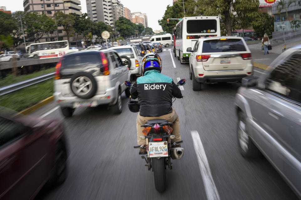 A Ridery app employee makes his way through traffic to pick up a customer, in Caracas, Venezuela, Wednesday, May 11, 2022. Ridery is one of at least three Venezuelan ride-sharing apps that launched during the pandemic — and which have taken advantage of a de facto switch of currencies from the Venezuelan bolivar to the U.S. dollar. (AP Photo/Matias Delacroix)