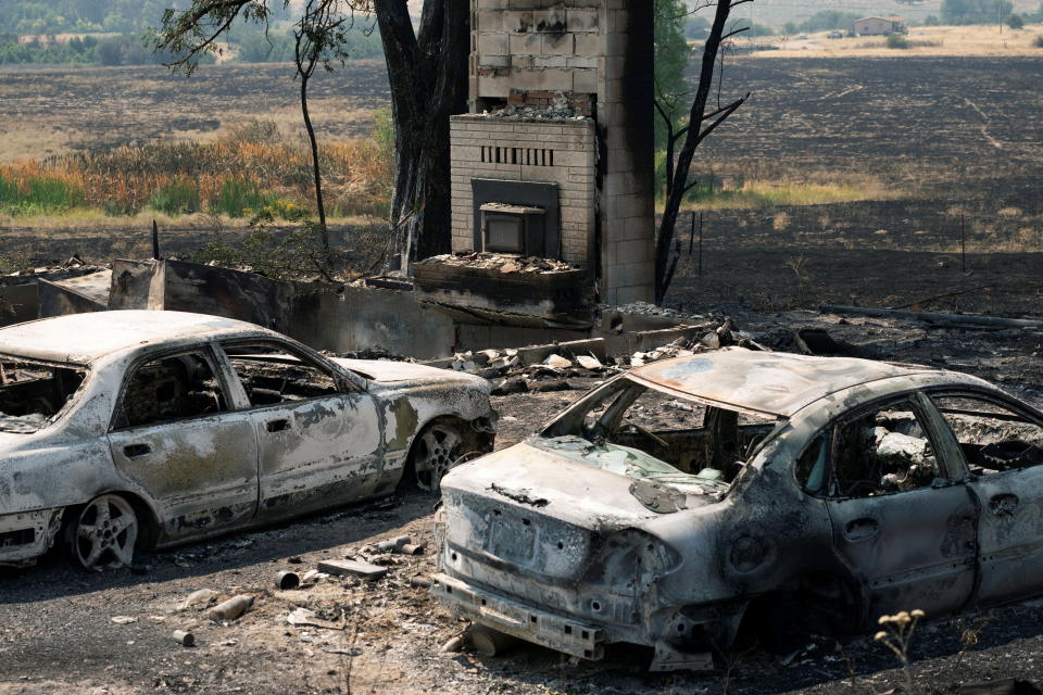 Burned cars sit outside a home destroyed by the Chuweah Creek Fire as wildfires devastate Nespelem in eastern Washington state.