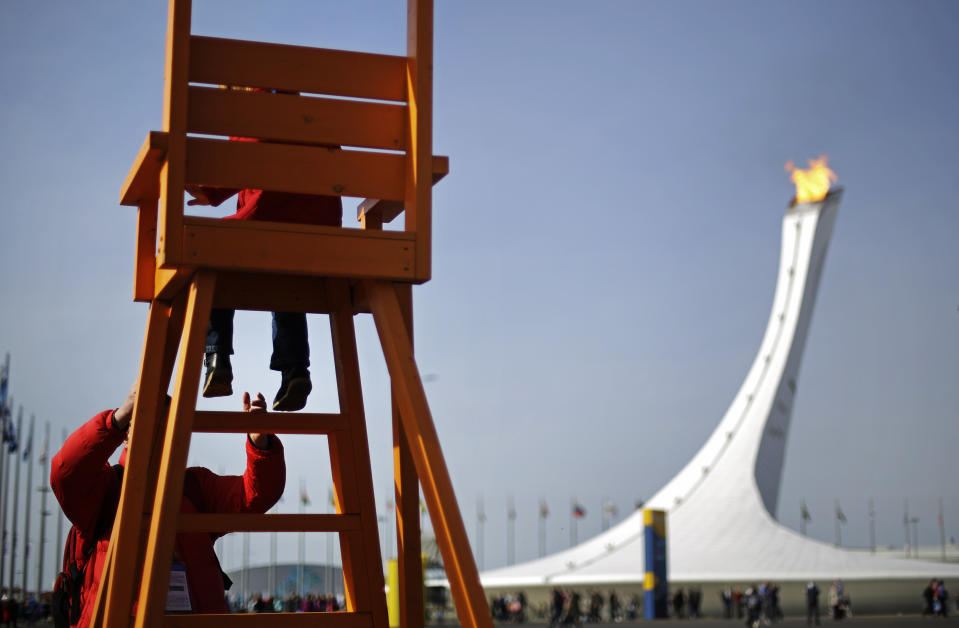 Anton Kirpichenkov helps his daughter, Polina, 4, both of Moscow, down from a large chair overlooking the Olympic cauldron at the 2014 Winter Olympics, Thursday, Feb. 20, 2014, in Sochi, Russia. (AP Photo/David Goldman)