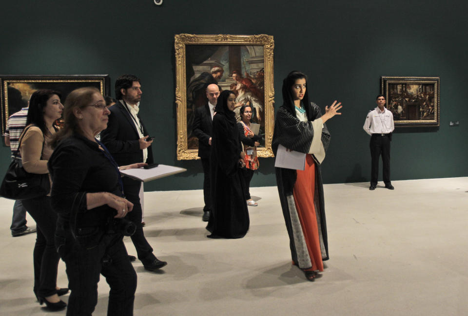 An Emirati guide, middle, talks about the paintings during a visit to a sample collection at the Abu Dhabi branch of the Louvre in Abu Dhabi, United Arab Emirates, Tuesday, April 16, 2013. No artistic subjects will be off limits at the Abu Dhabi branch of the Louvre museum as it builds its collection for a planned 2015 opening, a top overseer said Tuesday, in a city seeking to broaden its international profile but testing how far to open its conservative culture. (AP Photo/Kamran Jebreili)