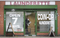 A man cleans the windows of a launderette in Leicester, England, Monday June 29, 2020. The central England city of Leicester is waiting to find out if lockdown restrictions will be extended as a result of a spike in coronavirus infections. (Joe Giddens/PA via AP)