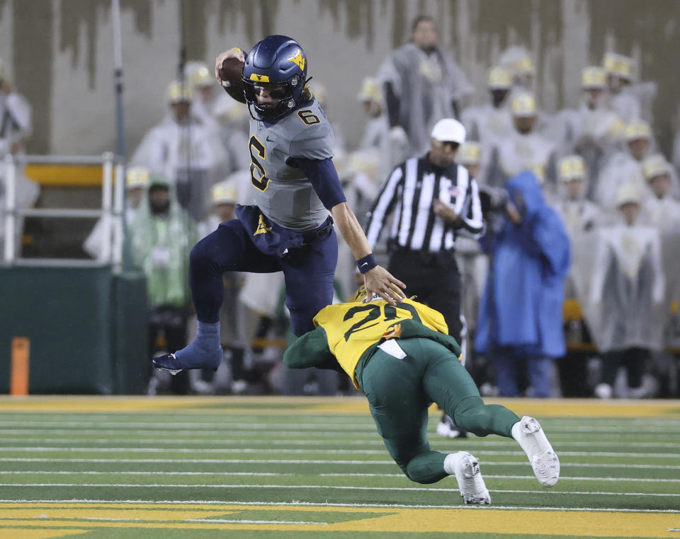 West Virginia quarterback Garrett Greene (6) leaps past Baylor safety Devyn Bobby (28) in the first half of an NCAA college football game, Saturday, Nov. 25, 2023, in Waco, Texas. (Jerry Larson/Waco Tribune-Herald, via AP)