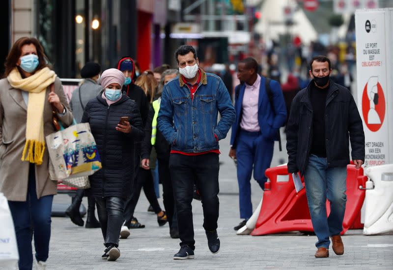 People wearing protective masks walk in a shopping street amid the coronavirus disease outbreak in Brussels