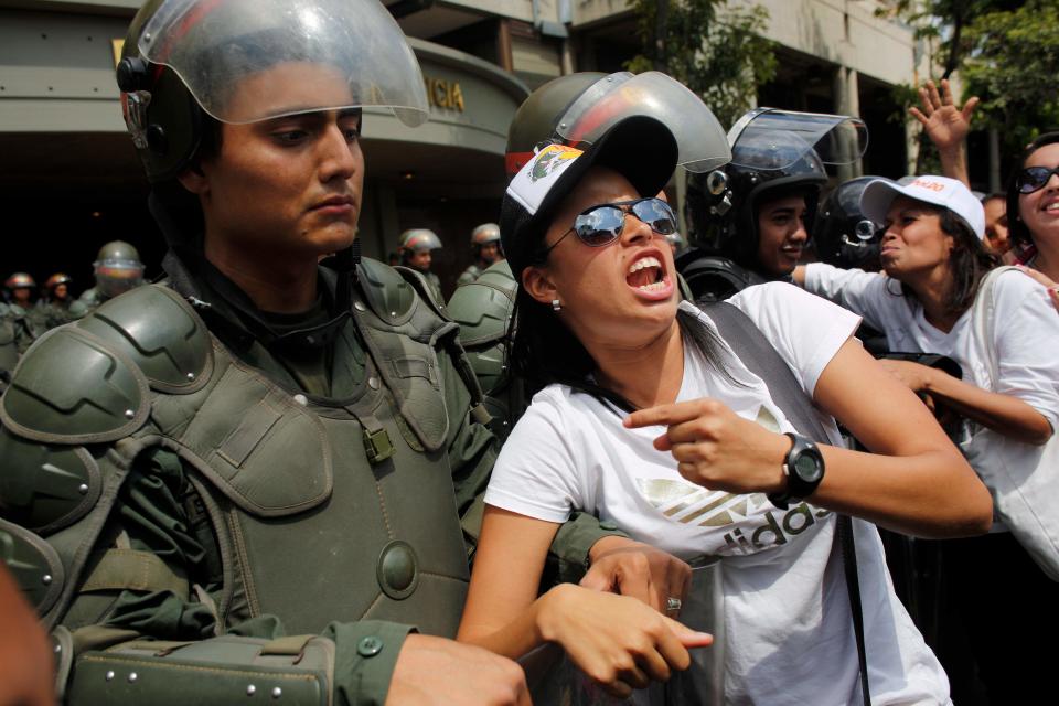 Supporters of opposition leader Leopoldo Lopez pose for a photos with Bolivarian National Guard, riot police officers outside the Palace of Justice in Caracas, Venezuela, Wednesday, Feb. 19, 2014. Following a dramatic surrender and a night in jail, Venezuelan opposition leader Leopoldo Lopez was due in court Wednesday to learn what charges he may face for allegedly provoking violence during protests against the socialist government in the divided nation. (AP Photo/Rodrigo Abd)