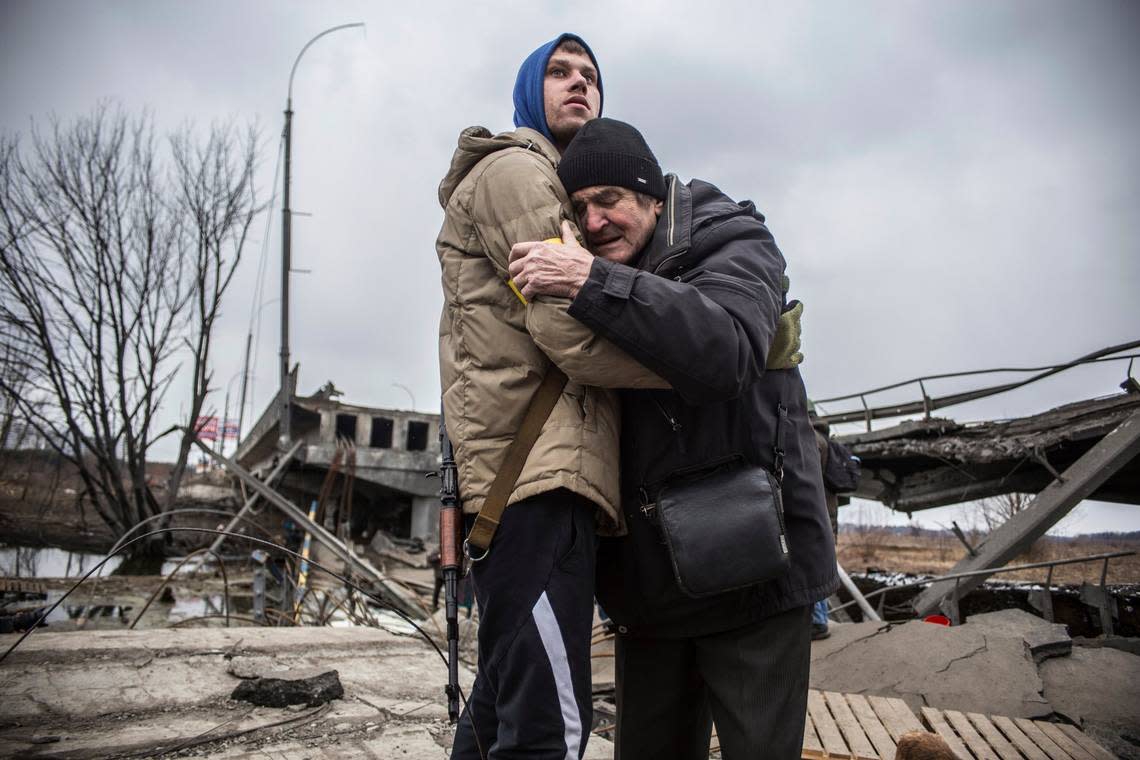 A Ukrainian Territorial Defence Forces member hugs a resident who leaves his home town following Russian artillery shelling in Irpin, on the outskirts of Kyiv, Ukraine in 2022.